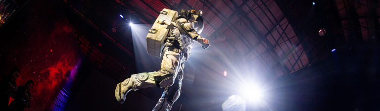 Astronaut acrobat floating against black background at event