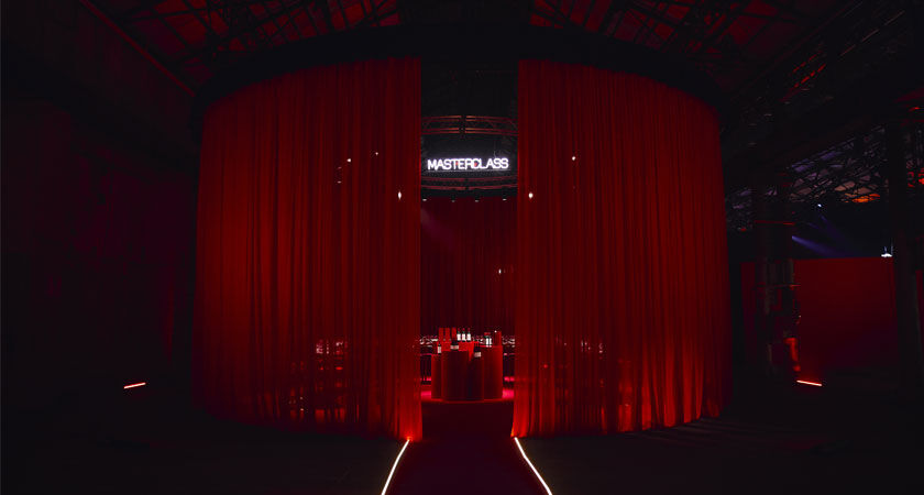 Red sheet curtains with a large round tasting table visible behind